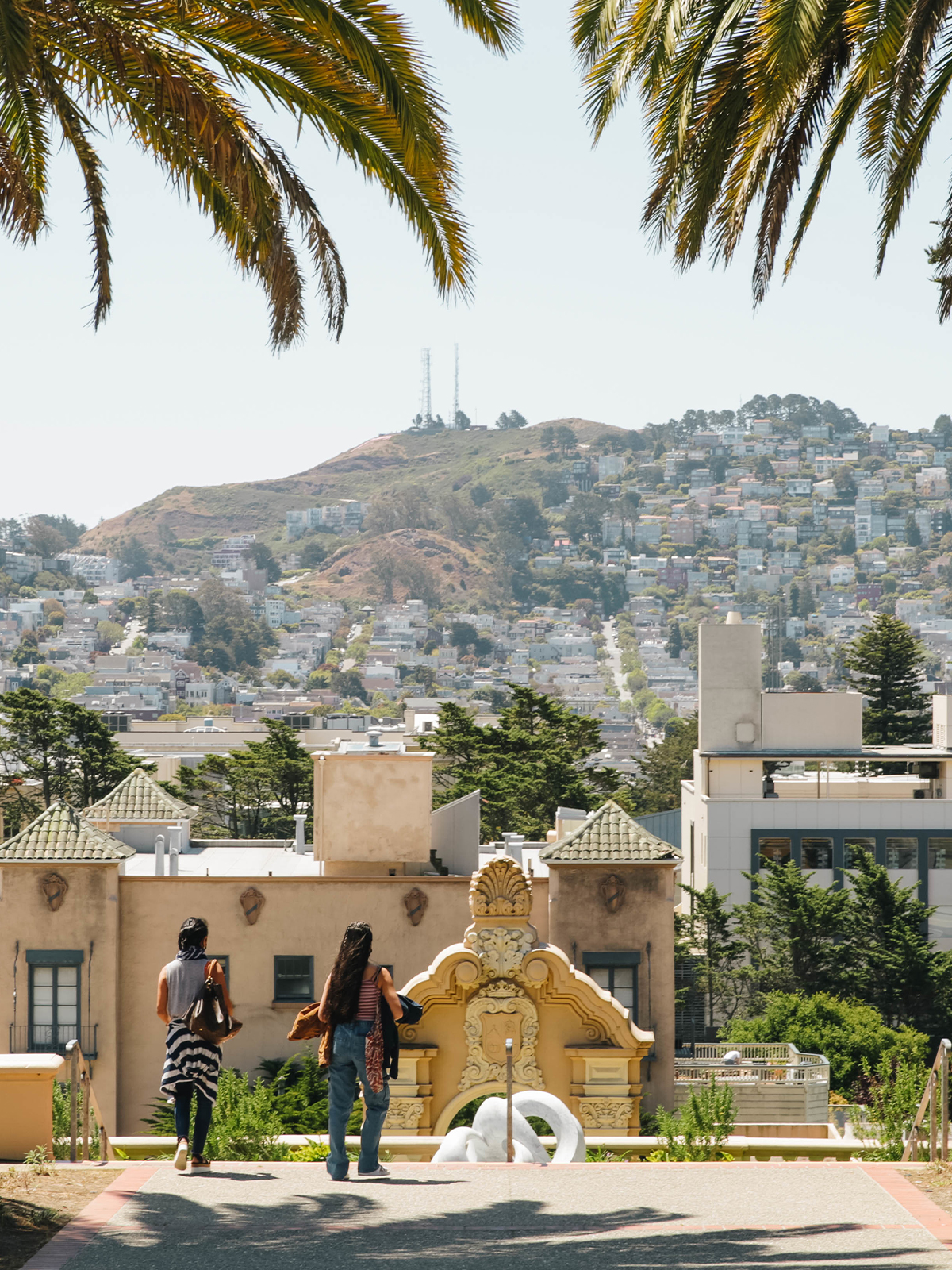 Two students look out over the University of San Francisco campus and the hills behind it.
