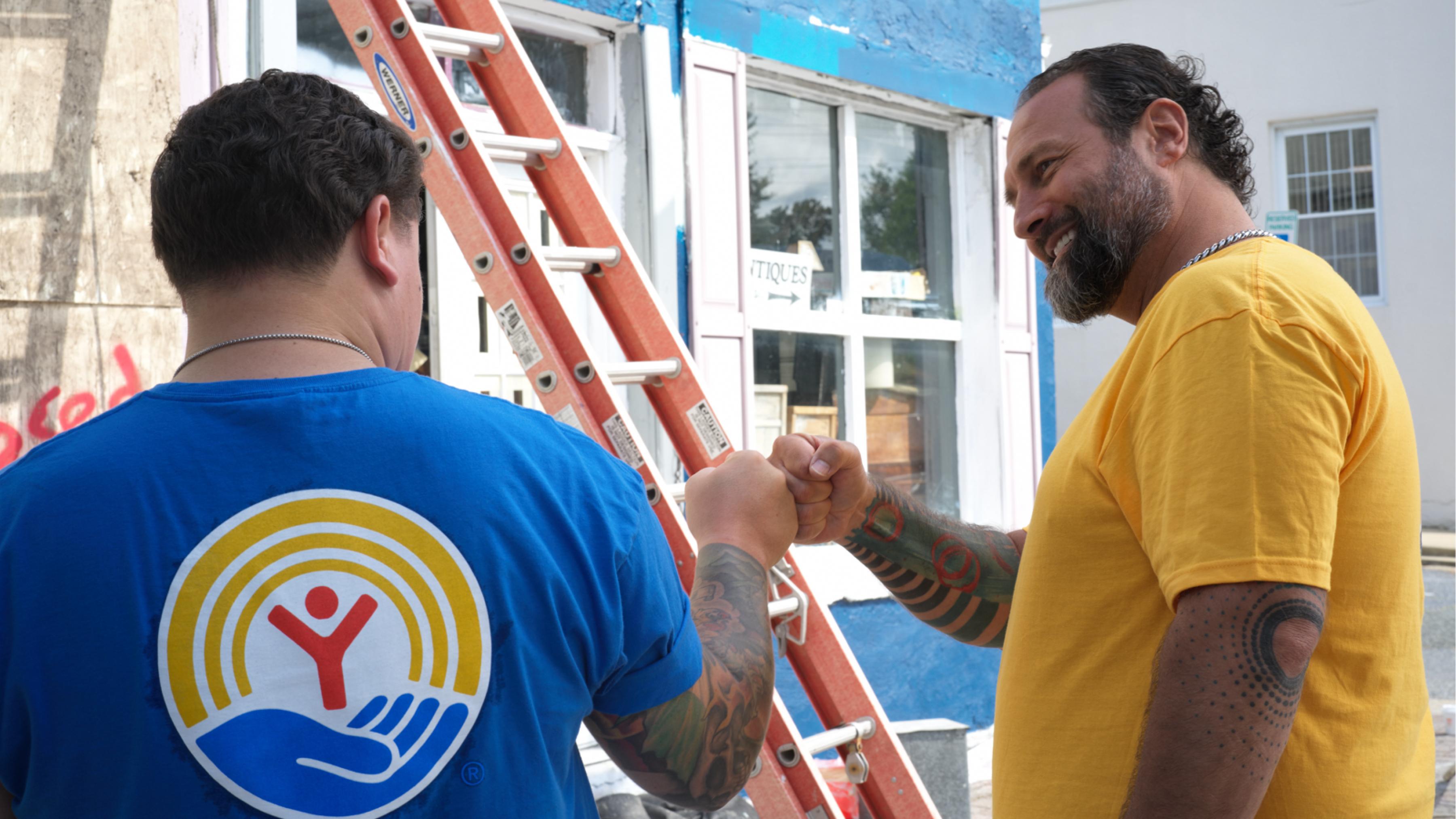 Two people high-fiving in front of a painted wall