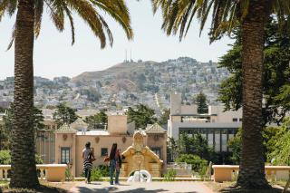 Two students look out over the University of San Francisco campus and the hills behind it.